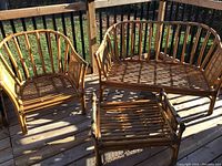 Photo showing entire rattan furniture set on deck in sunlight with loveseat, armchair, and coffee table arranged together.