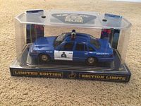 Blue and white RCMP model car in original display case with limited edition labeling.