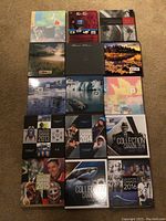 Fifteen hardcover albums arranged in three rows of five on a beige carpet.