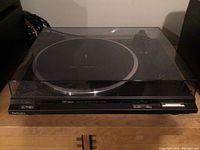 Full front view of the Technics turntable with transparent cover closed showing some scratches.