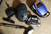 Top-down view of two canister vacuums plus various attachments