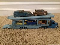 Side view of blue metal car transporter truck loaded with five model cars