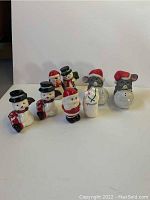 All eight vintage ceramic Christmas-themed salt and pepper shakers arranged in a row including snowmen, Santa Claus, chef, and mice characters.