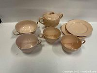 Pink peach petal ware sugar dish with lid, bowl, three teacups, and two side plates shown together.