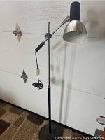 Full view of the lamp standing upright showing base, pole, adjustable arm, and shade.