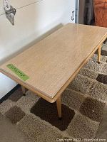 Photo of blonde wood mid-century modern coffee table showing rectangular top and tapered legs.