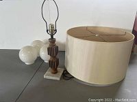 Full view of mid century lamp setup showing wooden lamp body on marble base, three separate globe bulbs, and large lampshade.