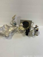 View of all items in the lot including ashtray, figurines, clock, vase, salt and pepper shakers arranged on a white surface.