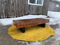 Angled front-side view showing teak top block and black angled legs