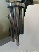 Close-up of the chrome tubular elements hanging from the chandelier showing patina and finish.