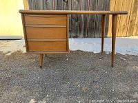 Front left view of desk showing three drawers and tapered leg