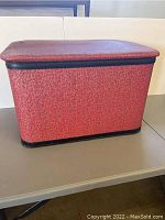 Photo of red rectangular vintage laundry hamper covered in textured vinyl with black trim.