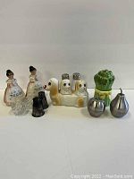 Seven salt and pepper shaker sets arranged in a single row on a plain surface with a white background. Photo focuses on lot contents and condition.