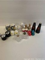 Photo showing all 9 vintage salt and pepper shakers, various styles and shapes, arranged on a white surface.