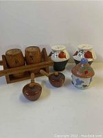 Photo showing all five salt and pepper shaker sets including wooden and ceramic items, some painted with leaves and one colorful shaker.