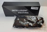 Photo showing the black Intelligent Heating gloves in plastic packaging alongside the branded box.