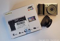 Photo showing CamKing 4K Full HD video camera with its original packaging and a detachable macro lens next to it.