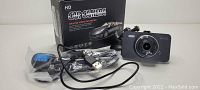 Photo showing boxed Full HD car camera with lens, USB cable, car charger, and suction mount.