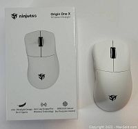 White Ninjutsu Origin One X wireless ultralight mouse next to its white box featuring branding and key features: 65G ultralight design, zero lag SnappyFire wireless technology, PAW3335 sensor.