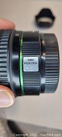 Close-up side view of the lens showing SMC Pentax DA branding and green ring.