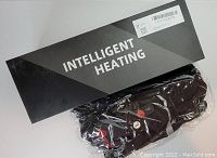 Photo of the black box labeled Intelligent Heating with sealed pair of black heated gloves in plastic wrapping.