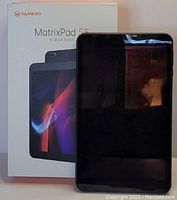 Photo of Vankyo MatrixPad S8 tablet and its original packaging box, showing front view of tablet turned off with screen reflecting light.