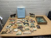 Collection of farm animal stand-up figures displayed on a table with a box containing wooden supports. Figures depict various farm animals in full color, vintage 1940s style artwork.