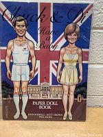 Front cover of the 'Chuck & Di Have a Baby' paper doll book showing illustrated figures of Chuck and Di with a British flag background.