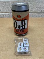 Duff Beer can container with ziploc bag holding five dice showing character faces from The Simpsons.