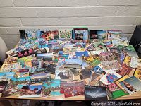 Wide view of a large collection of postcards spread out on a table showing diversity in imagery and size.