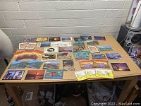 Table showing a large assortment of vintage Arizona postcards spread out, featuring landscapes, sunsets, Native American themes, and colorful designs.