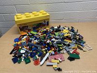 Yellow Lego Classic storage container with Mickey Mouse image and assorted Lego pieces spread out on table.