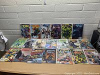 Photo showing 20 comic books featuring a mix of Marvel and DC titles including Cable, Iron Man, Batman, Fantastic Four, and others, displayed on a table.