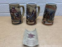 Front view of three ceramic Miller Beer collectible Birth of a Nation steins and a certificate of authenticity for Budweiser limited edition stein.