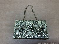 Front view of metal folding makeup compact organizer showing the mosaic reflective pattern and metal handle.