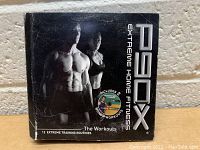 P90X Extreme Home Fitness DVD set box showing front cover with muscular male and female models, includes 12 extreme training routines.