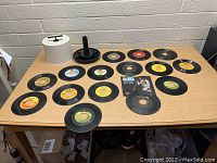 Top view of 45 rpm records laid out on table showing various colored labels and the white plastic tote holder for storing the records.