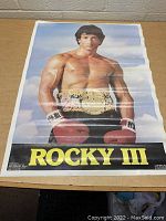 Front view of the vintage Rocky III 1982 movie poster showing the full image of the shirtless boxer with gloves and belt against a sky background.