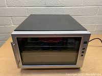 Wine refrigerator showing front angled view with glass door and stainless steel frame, three interior wire shelves visible, power cord visible at the back, control buttons on the right hand side of the door.