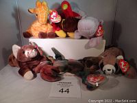 Seven Ty Beanie Babies plush toys displayed together, showing each with original tags attached to ears. Animals include giraffe, turkey, hippopotamus, monkey, lobster, otter, and beaver.