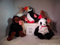 Five original Beanie Babies with tags including a panda, toucan, gorilla, deer, and cardinal.