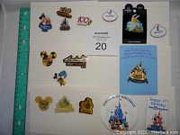 Top view of assorted Disney pins on white grid paper next to a ruler