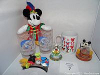 Full lot showing Conductor Mickey plush, two Mickey sorcerer glasses, EPCOT mug, two Mickey snowglobes, and Mickey collectible.