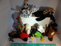 Photo showing various Beanie Babies including giraffe, ladybug, sheep, frog, and horse.