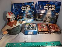 Wide shot of lot showing Micro Machines in packaging, puzzles, bandages box, and Anakin statue with a ruler for scale.