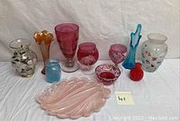Full lot showing various vases, goblets, nut-candy dish, and divided dish with different colors and shapes, arranged on white cloth.