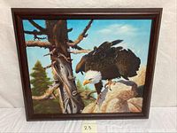 Painting of a bald eagle perched on rock by tree and sky background, framed in wood.