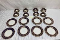 Eight stacked teacups on matching saucers, cobalt blue band, gold gilt motif