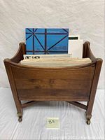 Front view of the wooden magazine rack holding assorted JFK memorabilia documents and booklets.