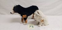 Side view of black and white plush dogs showing tags and size difference